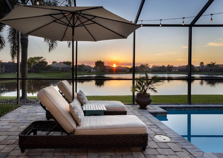 Paver pool deck and terrace overlooking the water at sunset in Manalapan